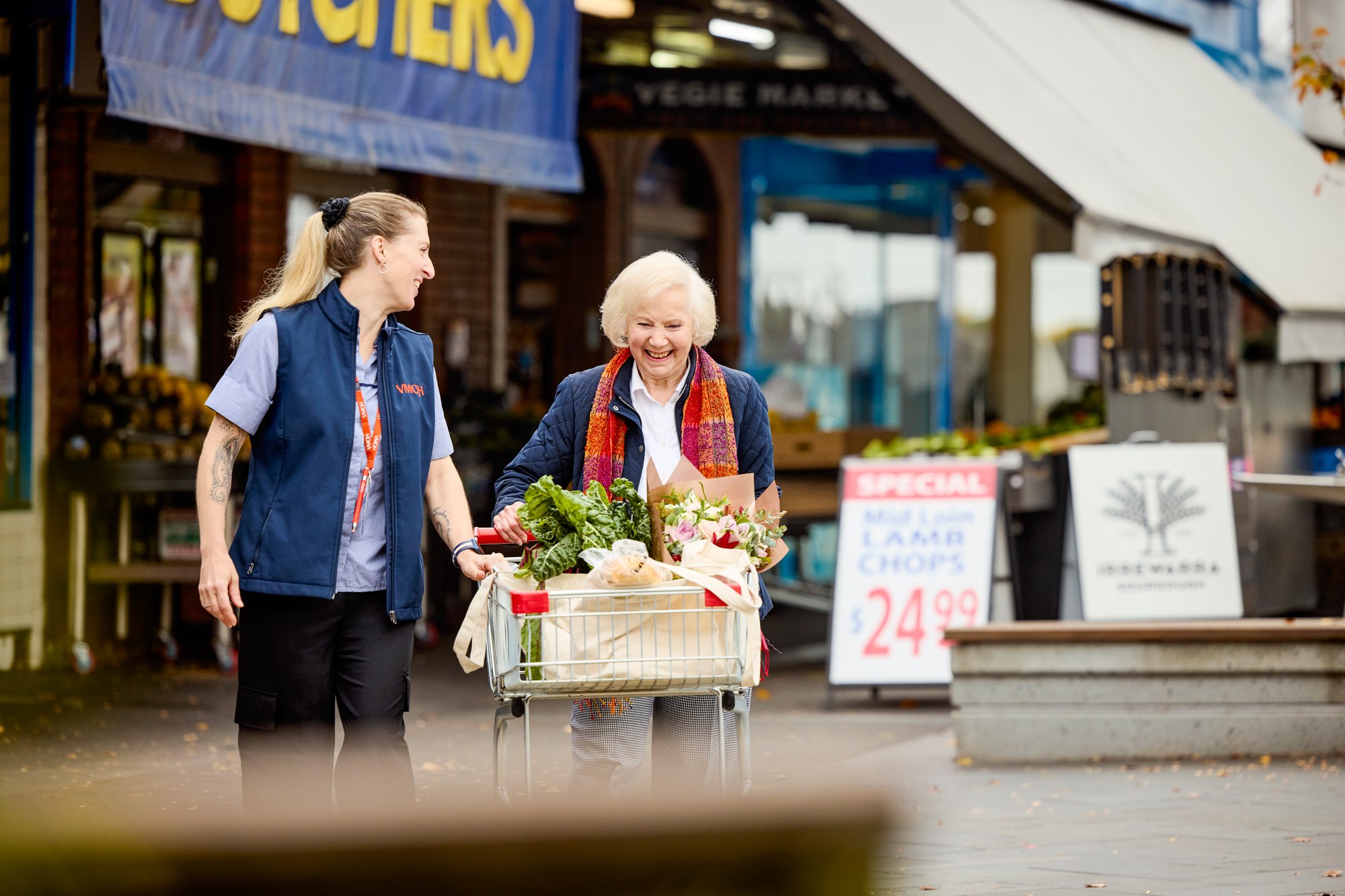 Home care worker helping an elderly lady with her grocery shopping in a trolley outdoors