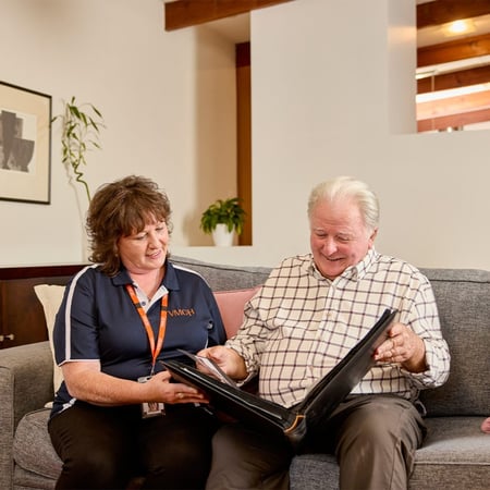 A support worker looking over paperwork for the Assistive Technology and Home Modifications (AT-HM) Scheme with a client in a living room.