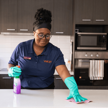 A woman cleaning a kitchen bench.