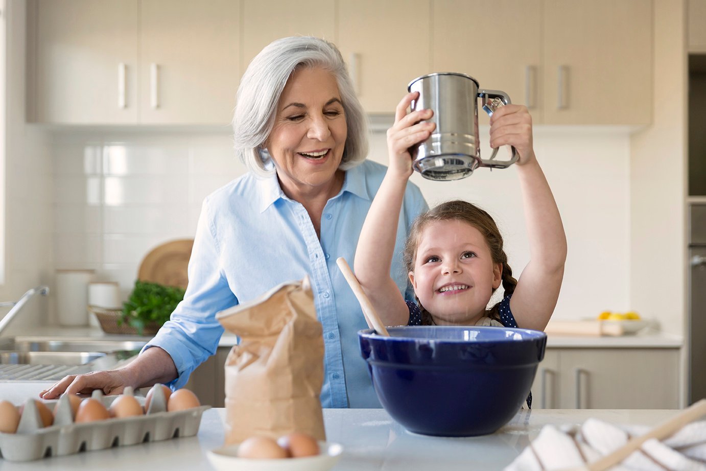 A senior woman in the kitchen baking with a small girl