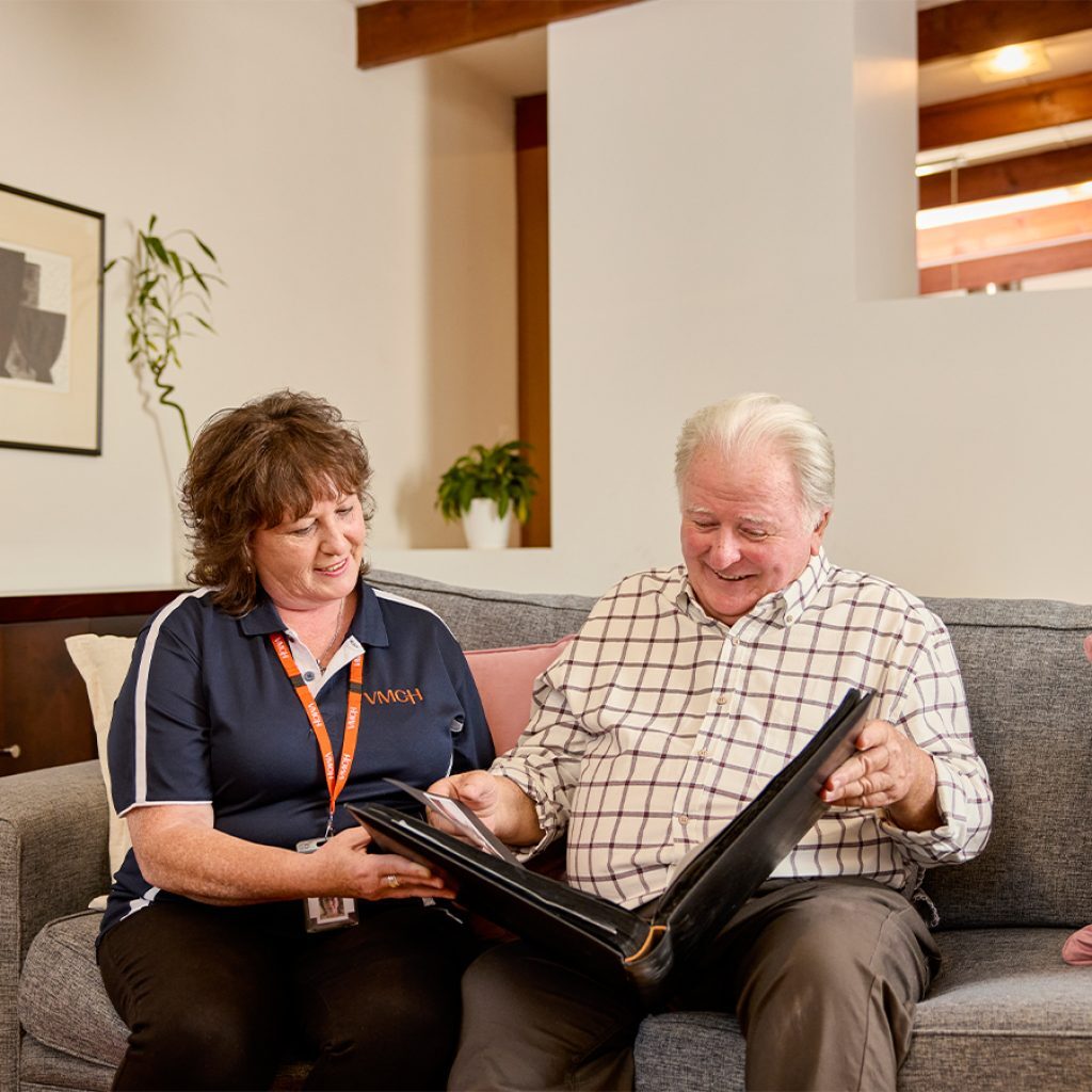 An older mana nd a support workers looking at paperwork on the couch.