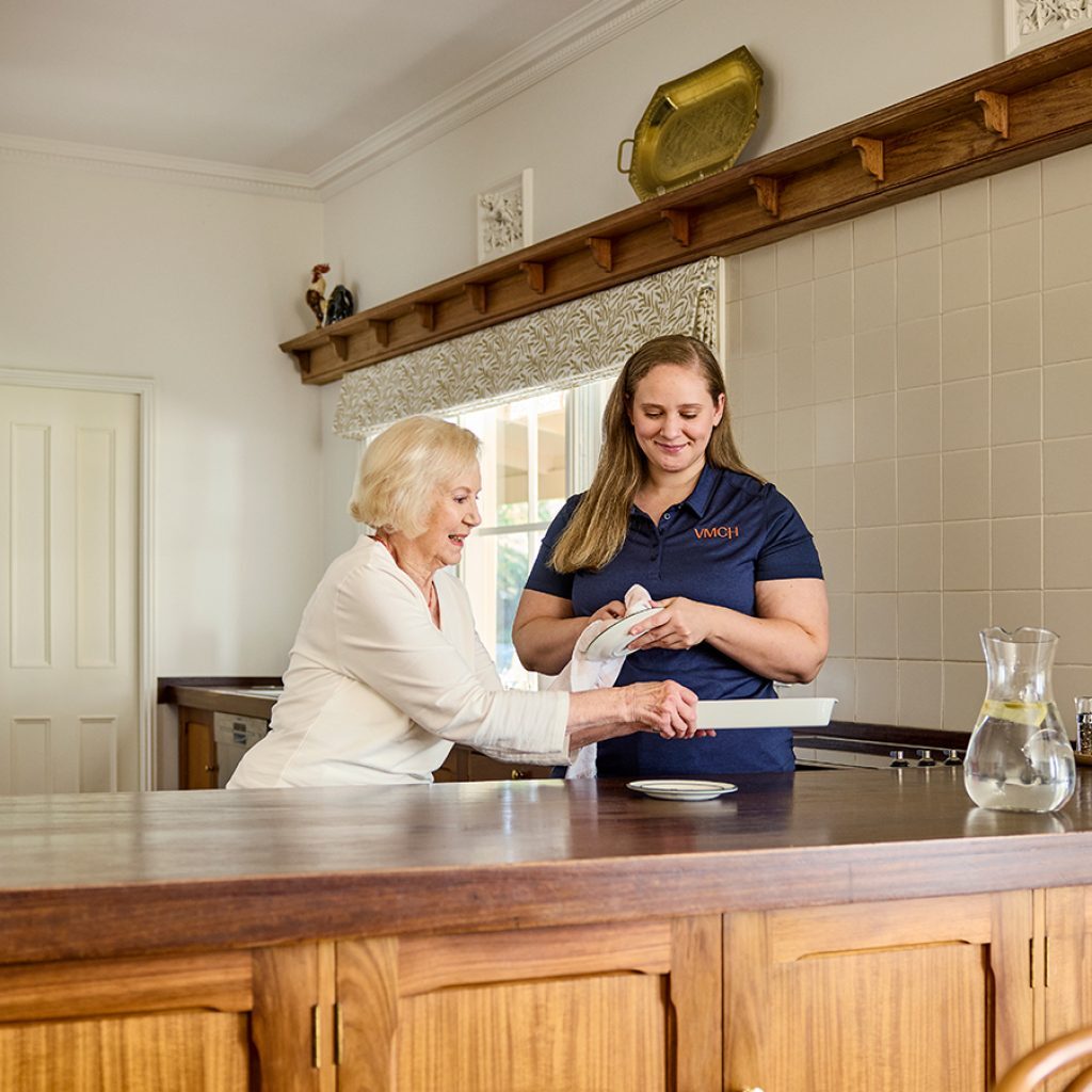A support worker helping a Support at Home client clean the kitchen as part of her everyday service.