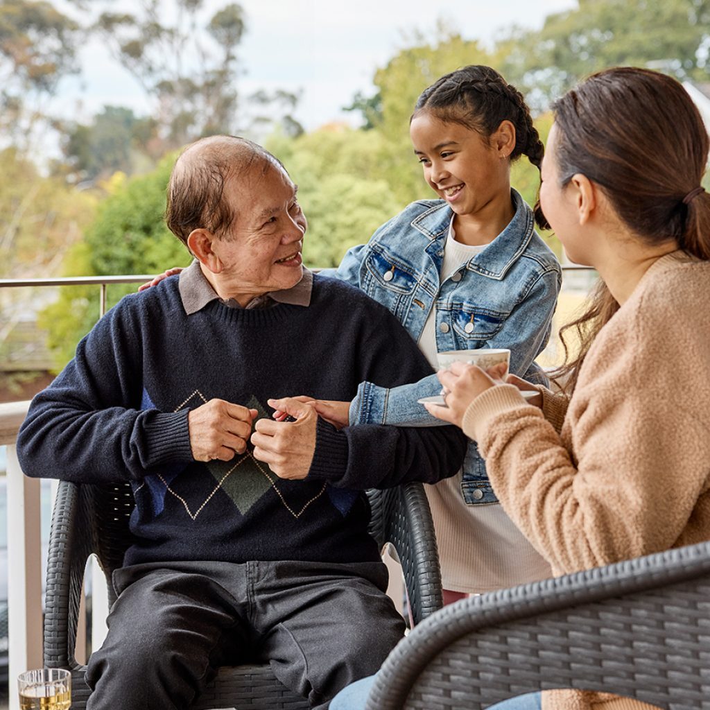 An older man having tea with a younger woman and a child.