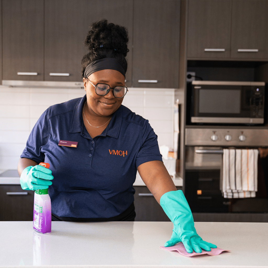 A woman cleaning a kitchen bench.
