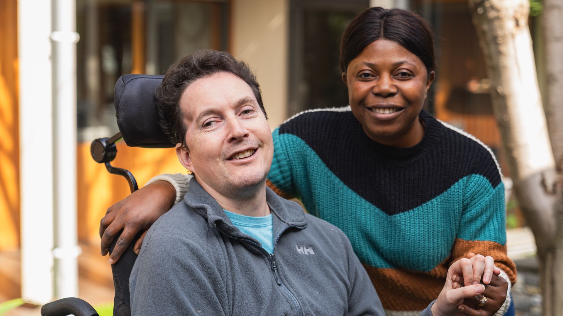 A man and a woman pose side by side and smile at the camera