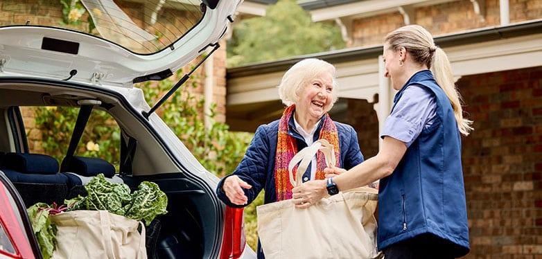 A carer getting groceries out of a car