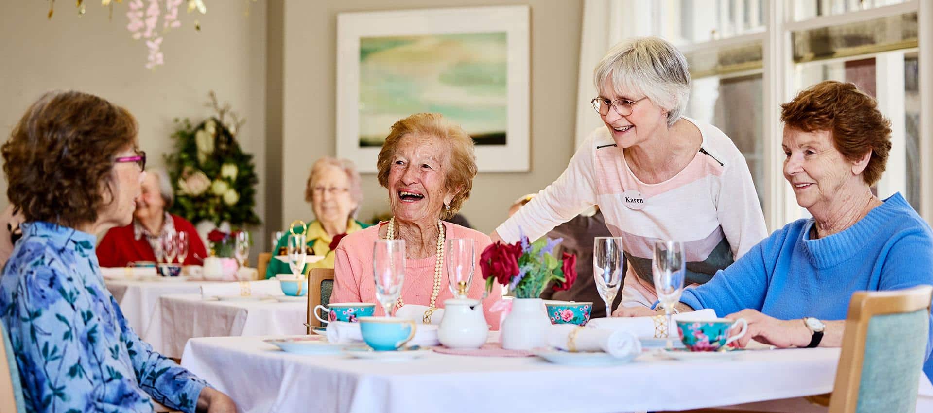 A group of woman sitting at a dining table, laughing